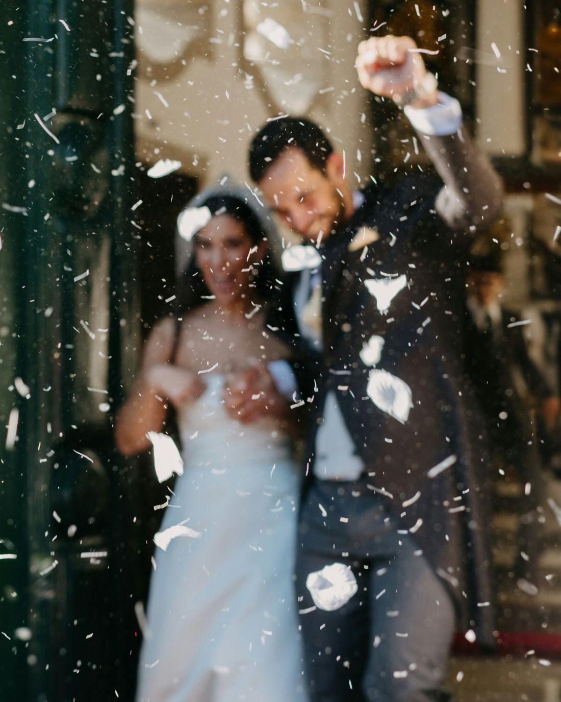 Una pareja de recién casados sale entre pétalos